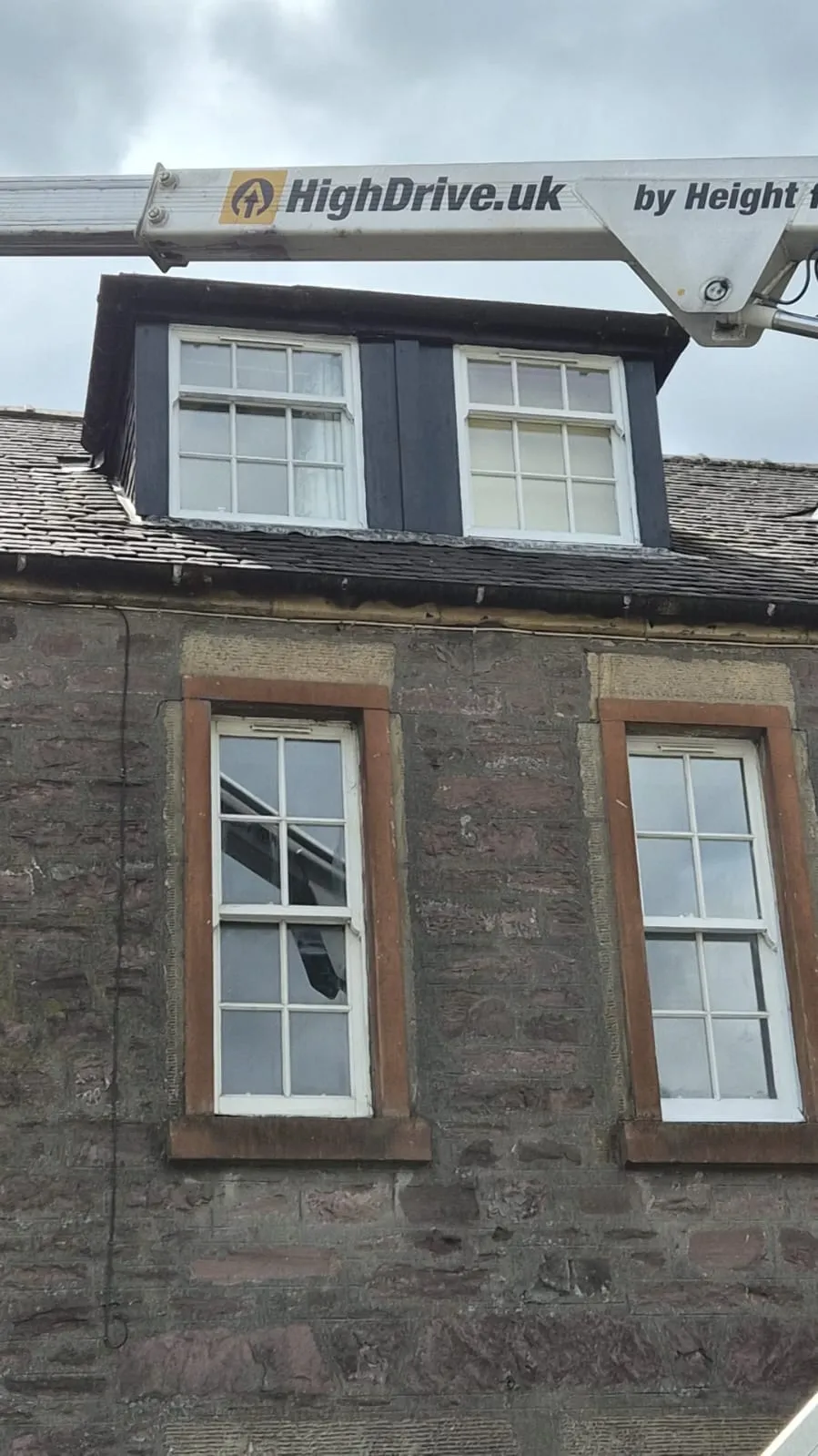 HighDrive cherry picker boom extending over a stone tenement dormer in Alloa