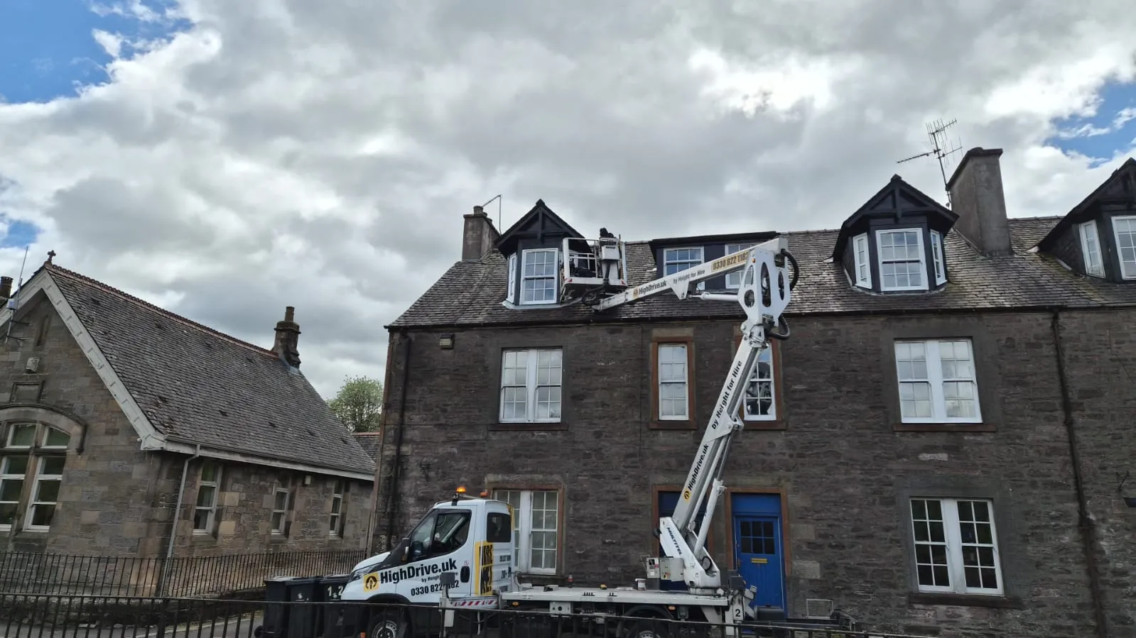 HighDrive cherry picker truck set up outside a row of stone tenements for roof and dormer work in Alloa