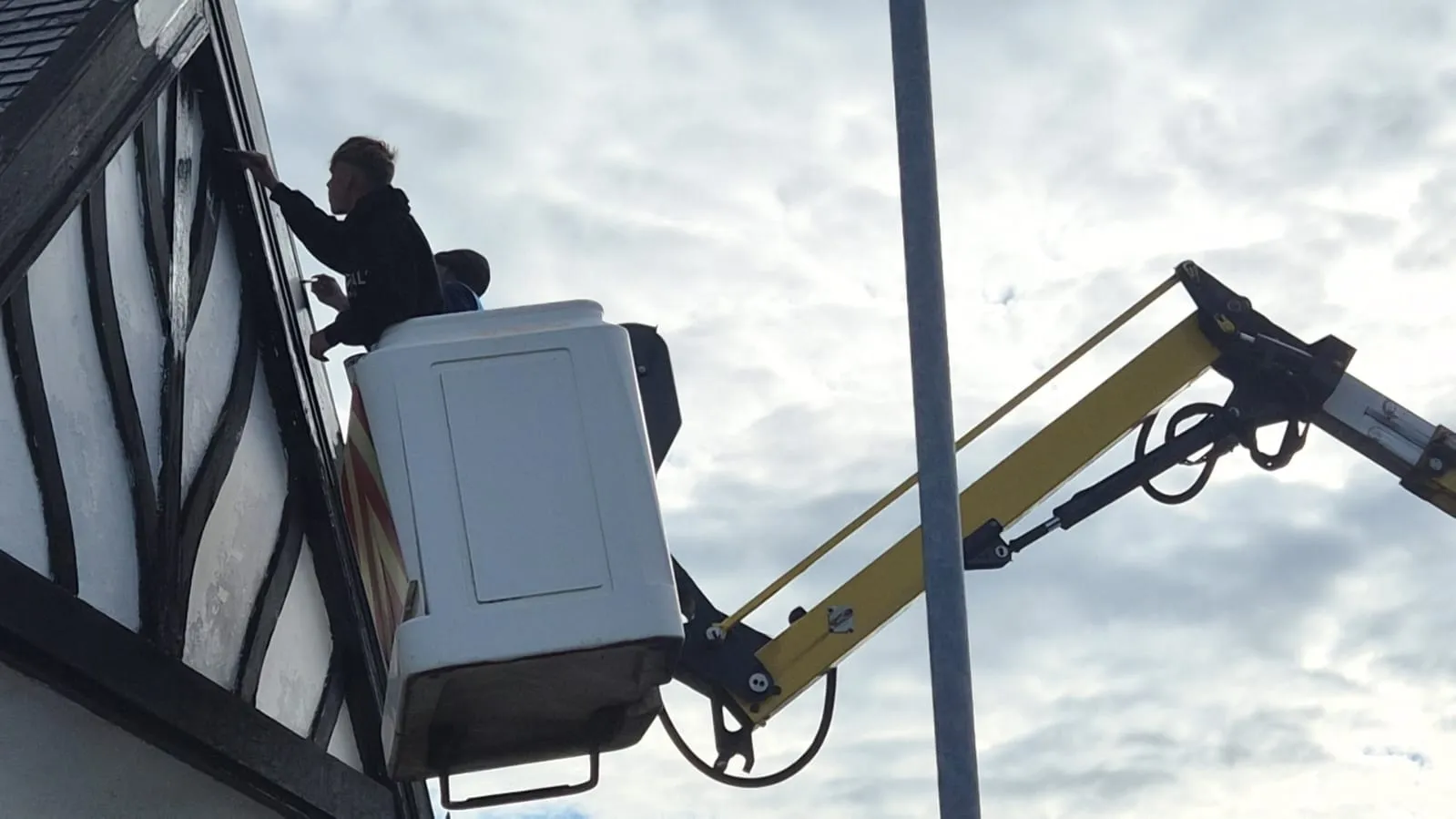 HS Roofing painting the timber detailing on a high gable from a cherry picker platform
