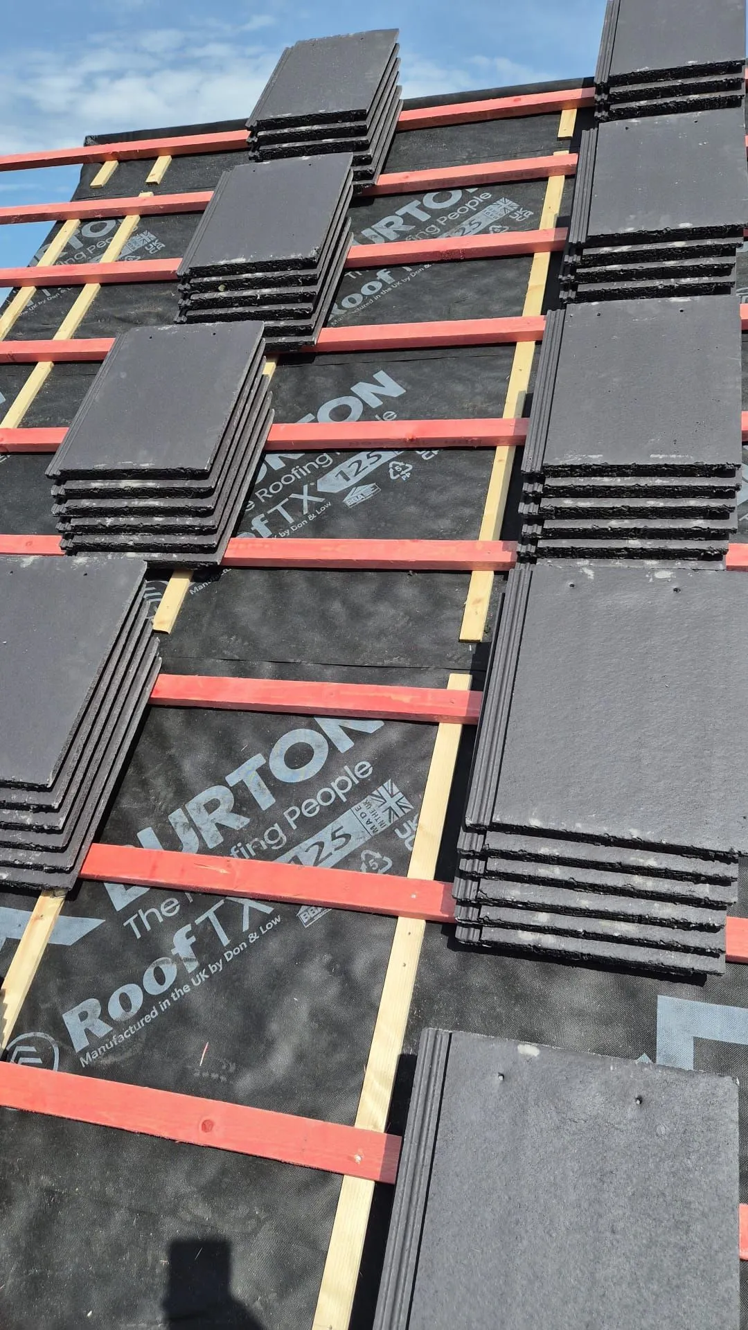 New slate grey tiles loaded out over breathable membrane and battens on a re-roof in Dalgety Bay