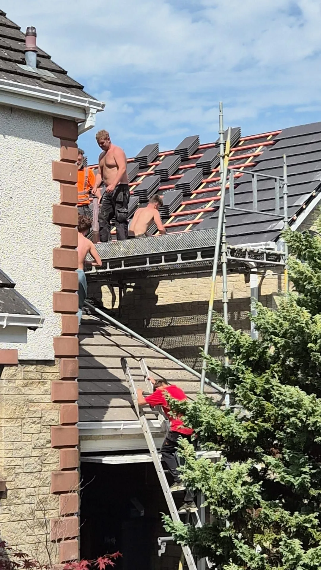 Roofing team laying out new tiles over battens on a house re-roof in Dalgety Bay