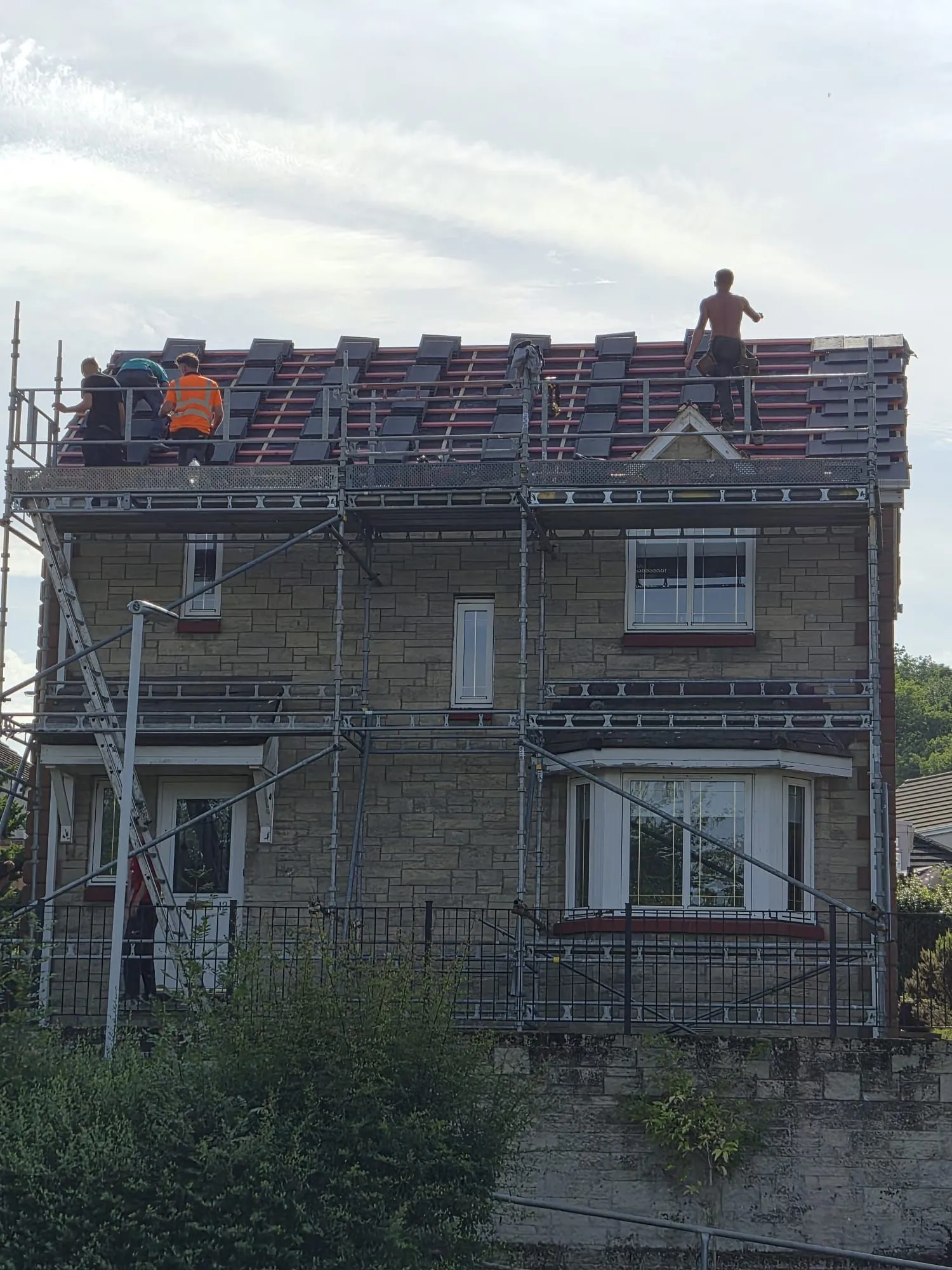 Roofing team laying new tiles across a detached house re-roof in Dalgety Bay, Fife