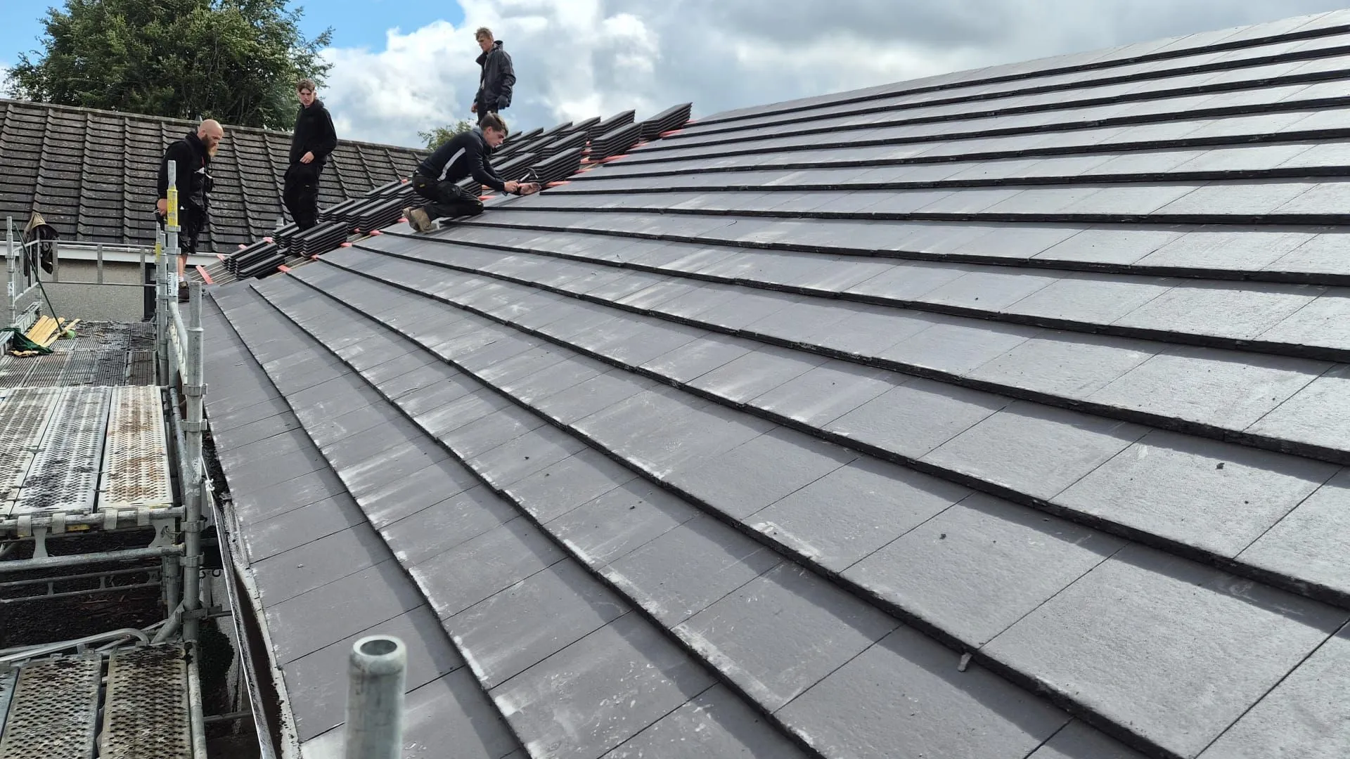 Close view of newly laid slate grey roof tiles running up to the ridge
