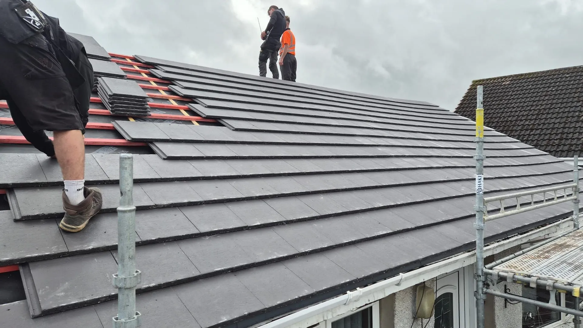 Roofing team laying new tiles over battens on a full re-roof in Lochgelly, Fife