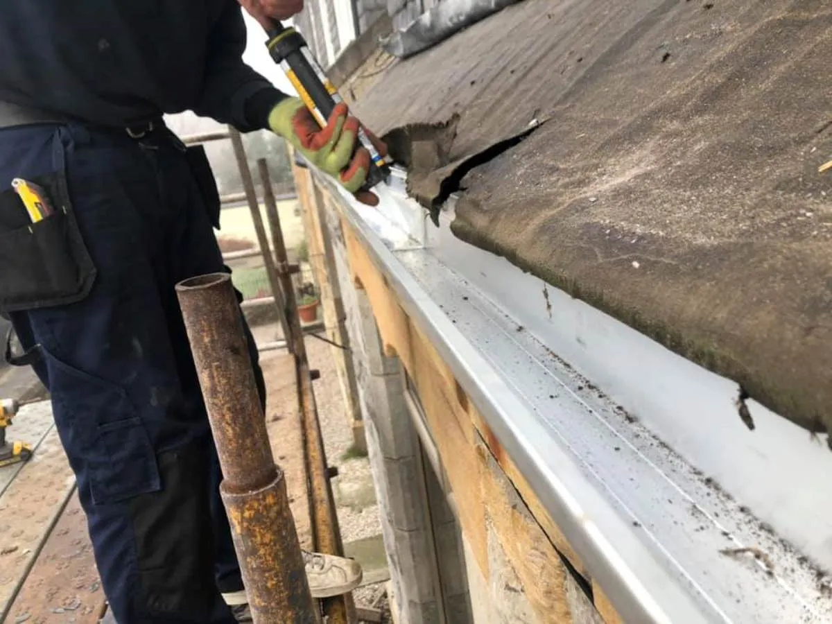 Roofer sealing new guttering on a roofline