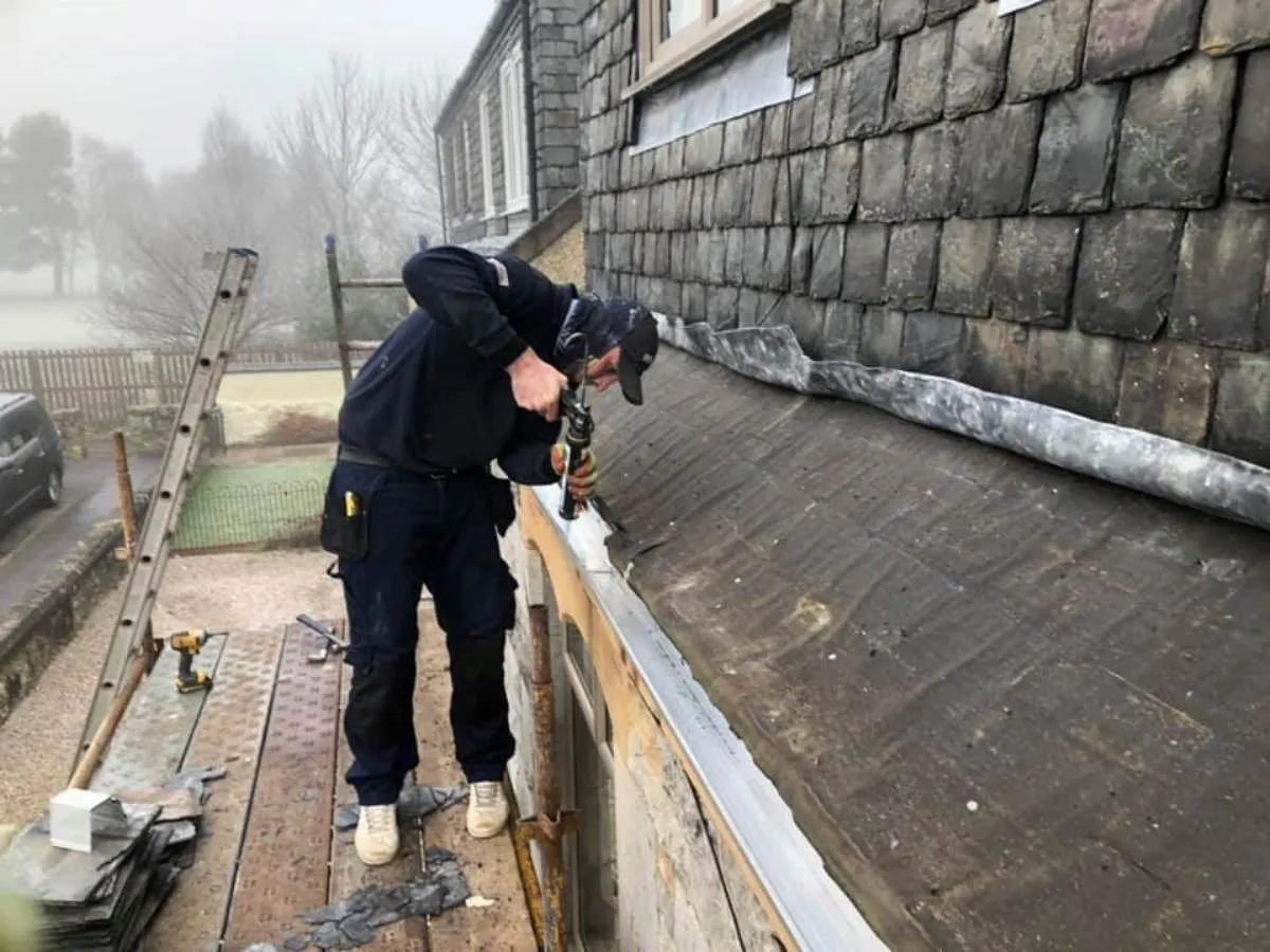 Roofer fitting new guttering on a slate roof in Clackmannanshire
